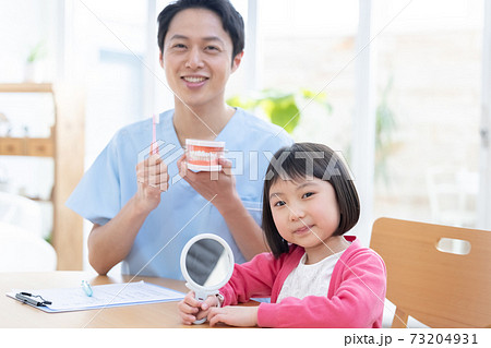 歯医者 歯磨き指導を受ける女の子と医師 歯医者 歯磨き指導を受ける女の子と医師 73204931