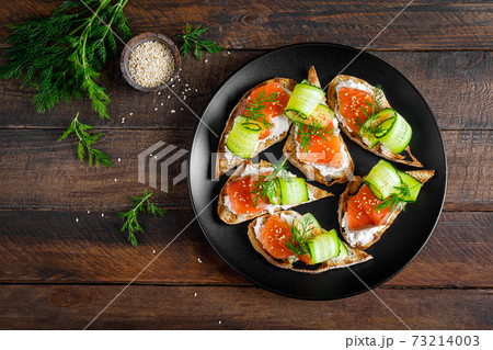 Toasts with salted salmon fish, ricotta cheese, fresh cucumber and ciabatta bread Toasts with salted salmon fish, ricotta cheese, fresh cucumber and ciabatta bread 73214003