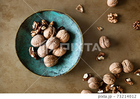 Walnuts in a bowl on a table, overhead view 73214012