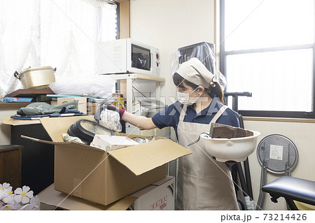散らかった部屋を片付ける女性作業員 73214426