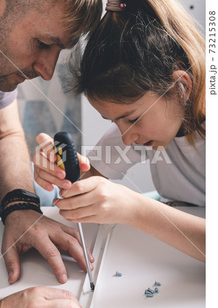 Father teaches daughter to use a screwdriver. Furniture assembly at home. Vertical shot. Selective focus Father teaches daughter to use a screwdriver. Furniture assembly at home. Vertical shot. Selective focus 73215308
