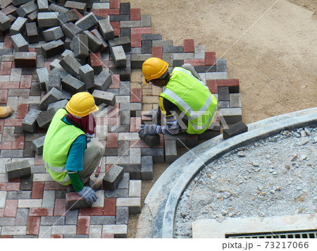 SEREMBAN, MALAYSIA -JULY 06, 2017: Construction workers installing and arranging precast concrete pavers stone for the road at the construction site. SEREMBAN, MALAYSIA -JULY 06, 2017: Construction workers installing and arranging precast concrete pavers stone for the road at the construction site. 73217066