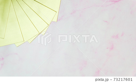 Blank golden cards stacked together in a fan shape at the top left corner, with pink marble background and copy space in the middle. 73217601