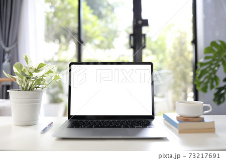 Laptop with white blank screen with coffee cup and books cozy home office Laptop with white blank screen with coffee cup and books cozy home office 73217691