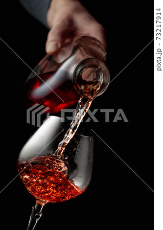 Pouring brandy in a glass goblet. Pouring brandy in a glass goblet. 73217914