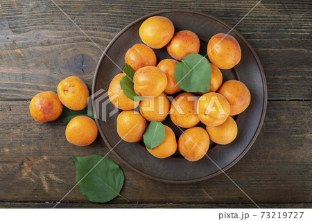 Delicious ripe apricots in a clay bowl on the table close-up. 73219727