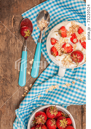 In a cup of yogurt, oat granola and fresh strawberries, on a blu 73220524
