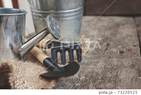 Garden tool, shovel, rake, watering can, bucket, bag on a wooden old brown background, close-up. Concept of gardening 73220525