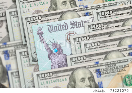 United States IRS Stimulus Check with Statue of Liberty Wearing Medical Face Mask Resting on Hundred Dollar Bills 73221076