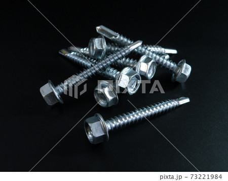 Self-tapping screws galvanized with a semicircular head and a hex head on a black background. Self-tapping screws galvanized with a semicircular head and a hex head on a black background. 73221984
