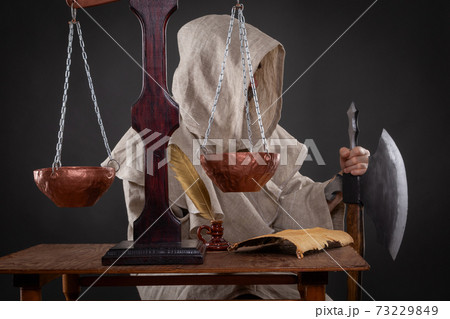 Halloween concept. The executioner of the holy inquisition with an ax weighing other people's sins 73229849
