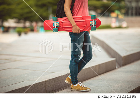 Asian woman with skatebaord in modern city Asian woman with skatebaord in modern city 73231398