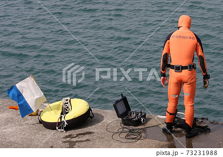 ウェットスーツを着て海面を見下ろす、消防救助隊員（後ろ姿） 73231988