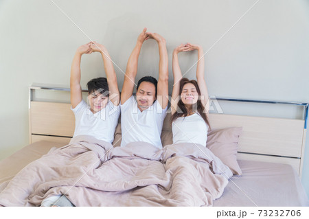 Three friends lying in bed woke up and stretched in the morning. Three friends lying in bed woke up and stretched in the morning. 73232706