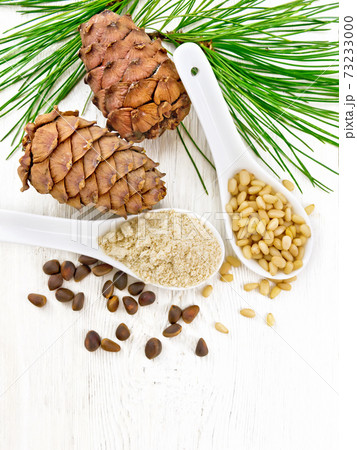 Flour cedar and nuts in two spoons on light board top 73233000