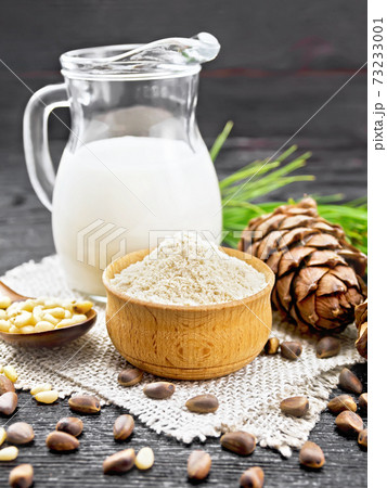Flour cedar in bowl with nuts on wooden board 73233001