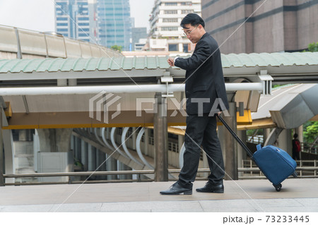 Middle-aged businessman walking suitcase in modern city. 73233445