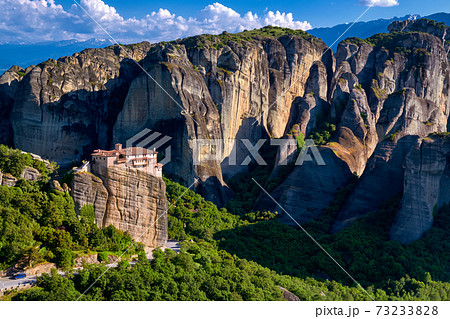 View of Meteora valley, Greece at midday. Moni Agias Varvaras Roussanou nunnery on cliff top, forests, hills, giant rocks. UNESCO World Heritage 73233828