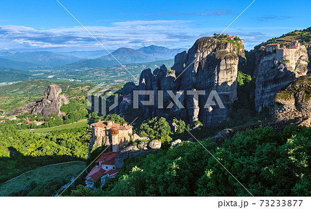 Morning view of Moni Agias Varvaras Roussanou in morning, Meteora, Greece and Varlaam monastery, rocks and valley. Rich foliage. UNESCO World Heritage 73233877