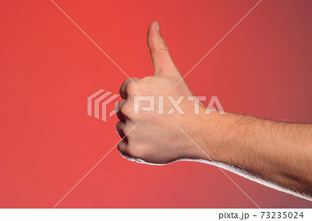 Close-up of a hand with a fingernail up of an isolated on a red background Close-up of a hand with a fingernail up of an isolated on a red background 73235024