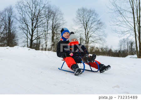 boy and girl are riding on sleds 73235489