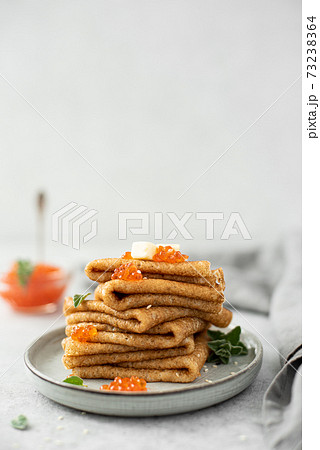 a stack of thin pancakes with red salted caviar and butter 73238364