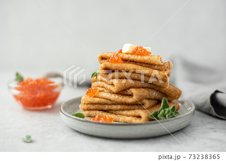 a stack of thin pancakes with red salted caviar and butter 73238365
