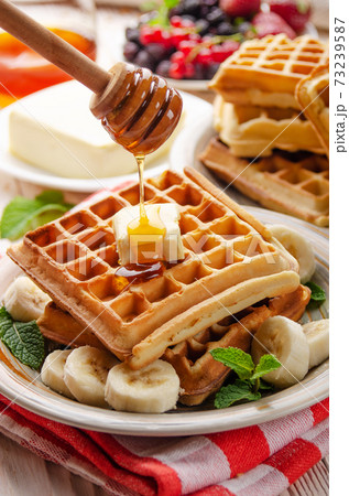 Belgian waffles served with butter banana mint leaf and syrup 73239587