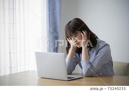 パソコンの前で頭を抱える若い女性 73240233