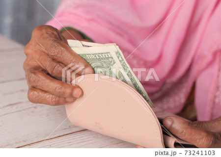 Close up of senior women hand saving cash in wallet  73241103
