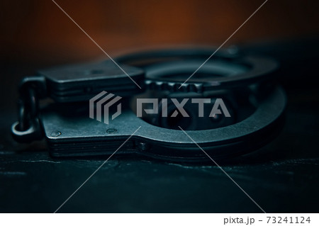 Handcuffs and the muzzle of hand gun close up. Handcuffs and the muzzle of hand gun close up. 73241124