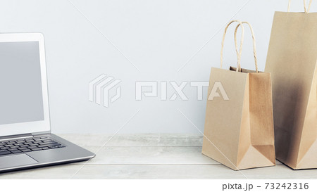 Laptop and paper shopping bags. Packages delivery online orders Laptop and paper shopping bags. Packages delivery online orders 73242316
