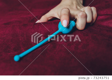 Woman holding anal balls in bed close-up. 73243751