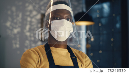 Black barista in face mask and shield in cafe Black barista in face mask and shield in cafe 73246530