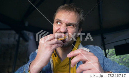 portrait of angry man eating hamburger at fast food cafe portrait of angry man eating hamburger at fast food cafe 73246717