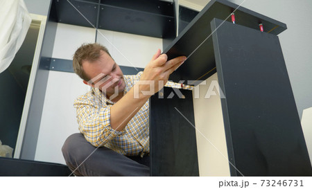 handsome man collects furniture at home in the room. copy space 73246731