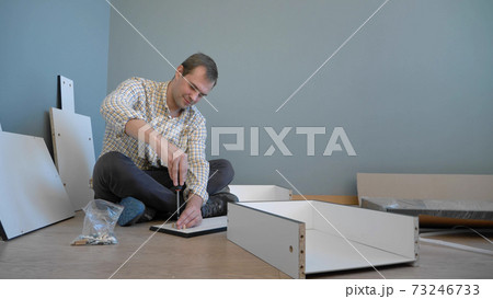 handsome man collects furniture at home in the room. copy space 73246733