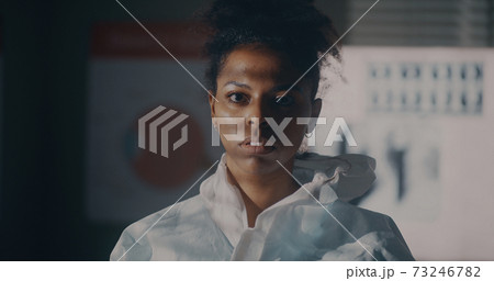 Ethnic medical practitioner taking off protective suit 73246782