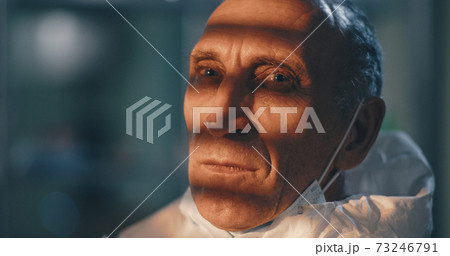 Tired mature doctor taking off protective suit Tired mature doctor taking off protective suit 73246791