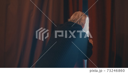 Anxious actor peeking through curtains on stage Anxious actor peeking through curtains on stage 73246860