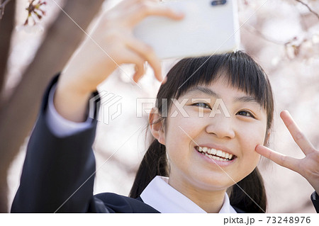 スマホで自撮りをする新中学生 小学校卒業 入学イメージの写真素材