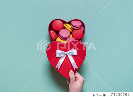 Macarons in a gift box. Woman hand opening box with macarons. 73250596