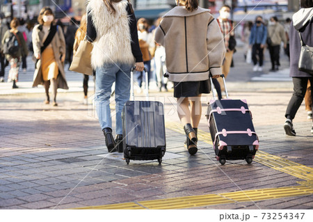 渋谷駅前をキャリーバッグを引いて歩く若い女性の二人組の後ろ姿 渋谷駅前をキャリーバッグを引いて歩く若い女性の二人組の後ろ姿 73254347
