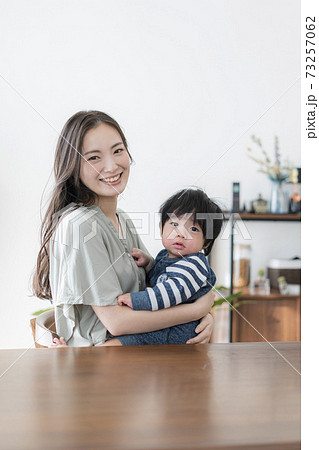 0歳の赤ちゃんを抱えたままパソコンを操作する若い母親 0歳の赤ちゃんを抱えたままパソコンを操作する若い母親 73257062