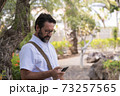 Portrait of adult caucasian man use mobile cellular smart phone outdoor at the park - modern people and connection technology - search the web with free wifi internet signal 73257565