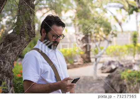Portrait of adult caucasian man use mobile cellular smart phone outdoor at the park - modern people and connection technology - search the web with free wifi internet signal Portrait of adult caucasian man use mobile cellular smart phone outdoor at the park - modern people and connection technology - search the web with free wifi internet signal 73257565