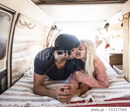 Love and travel with young caucasian couple kiss and love inside a trendy van vehicle during life or vacation leisure activity - concept of people together in tiny house alternative Love and travel with young caucasian couple kiss and love inside a trendy van vehicle during life or vacation leisure activity - concept of people together in tiny house alternative 73257569