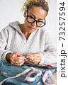 Portrait of middle age caucasian woman working at home tailoring with clothes to repair or hand made - tailor job with independent people in home work leisure activity 73257594