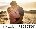 Kiss and love couple outdoor with two young man and woman kissing and hugging in a golden sunset background - people enjoy together forever life - concept of different ages male female 73257595