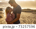 People in love and golden sunset outdoor - man and woman couple hug and look each other with beach in background - concept of protection and life together forever 73257596